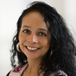 A woman with long black hair stands and smiles